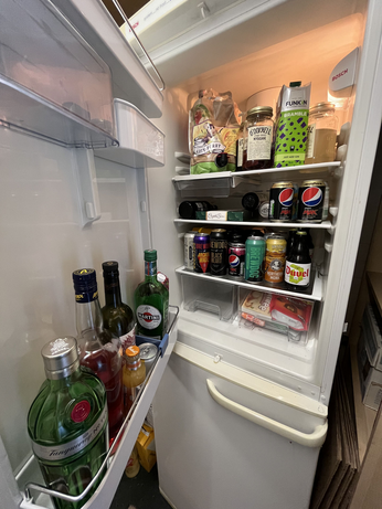 Domestic fridge full of alcoholic drinks and chocolates.