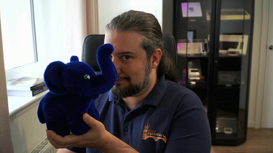 Jimmy Angelakos recording his talk for POSETTE 2024, he's half-hiding behind a Slonik elephant plushie